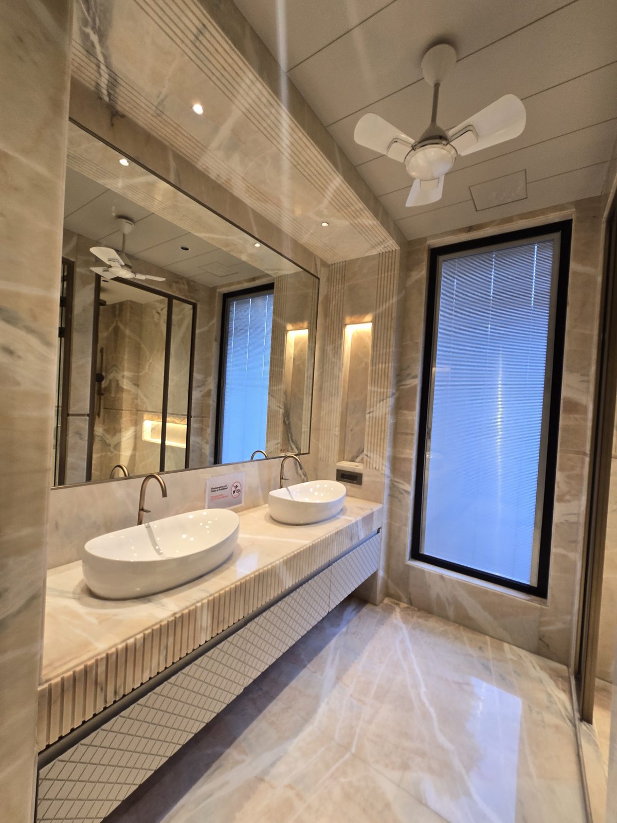 Twin vessel basins on a beige marble counter in an Ekum Homes builder floor bathroom in South Delhi