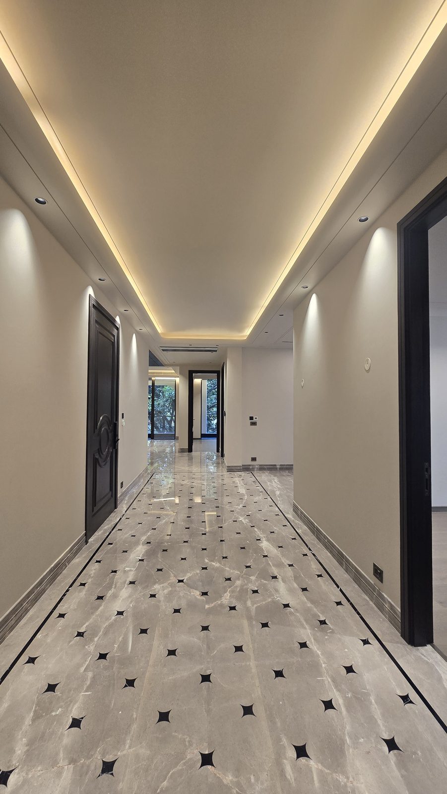 Corridor in an Ekum Homes South Delhi builder floor with star-inlay marble flooring and recessed cove lighting