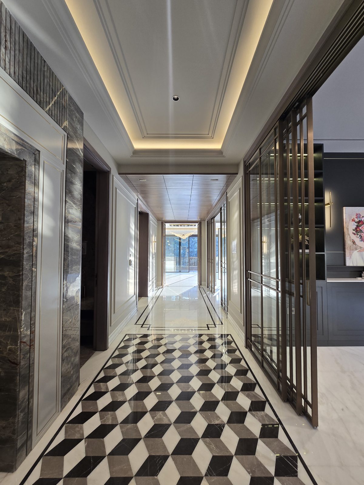 Entrance foyer of an Ekum Homes builder floor in South Delhi with geometric marble inlay flooring and bronze glazed partitions
