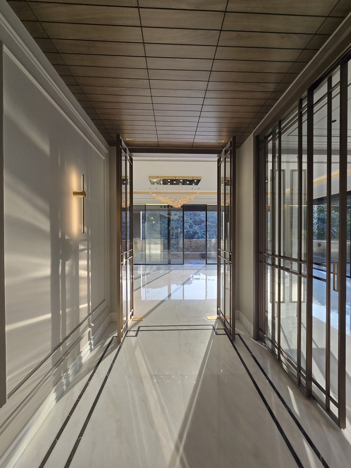 Entrance passage with bronze-framed glazed doors and a wood-panelled ceiling in an Ekum Homes South Delhi builder floor