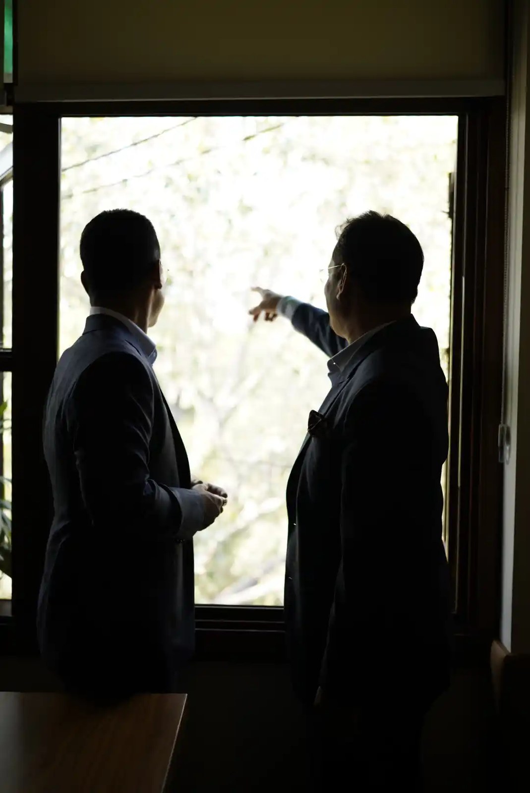 The leadership of Ekum Homes in silhouette at a window, looking out over a South Delhi site
