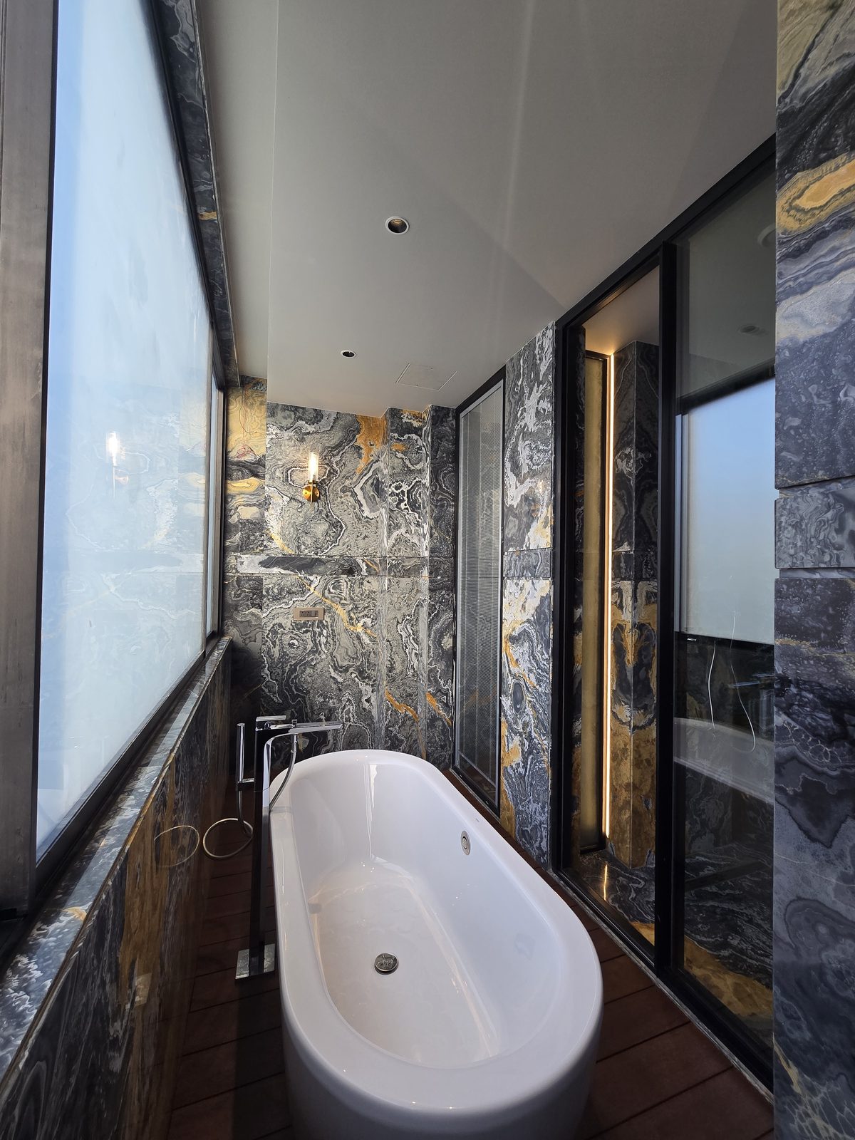 Master bathroom in an Ekum Homes South Delhi builder floor with a freestanding bathtub and dramatic black-and-gold veined marble