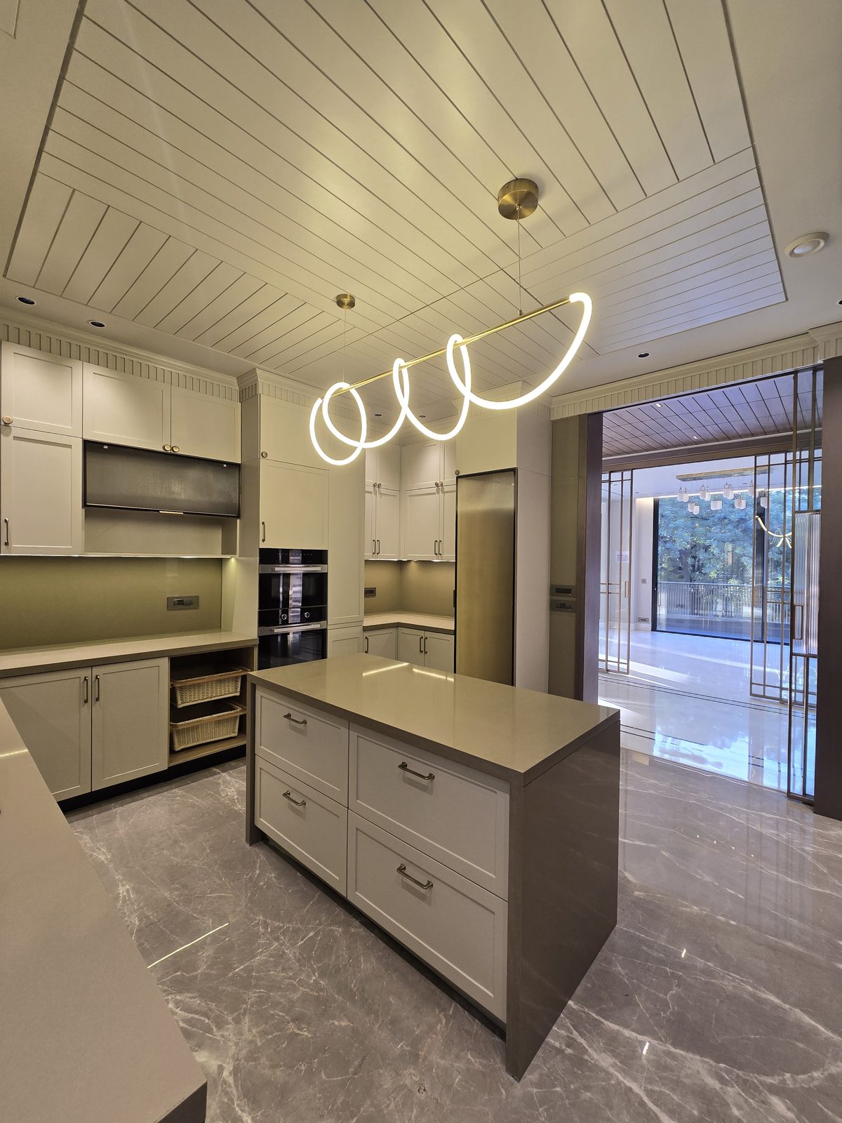 Modular kitchen with a central island and sculptural ring pendant in an Ekum Homes South Delhi builder floor