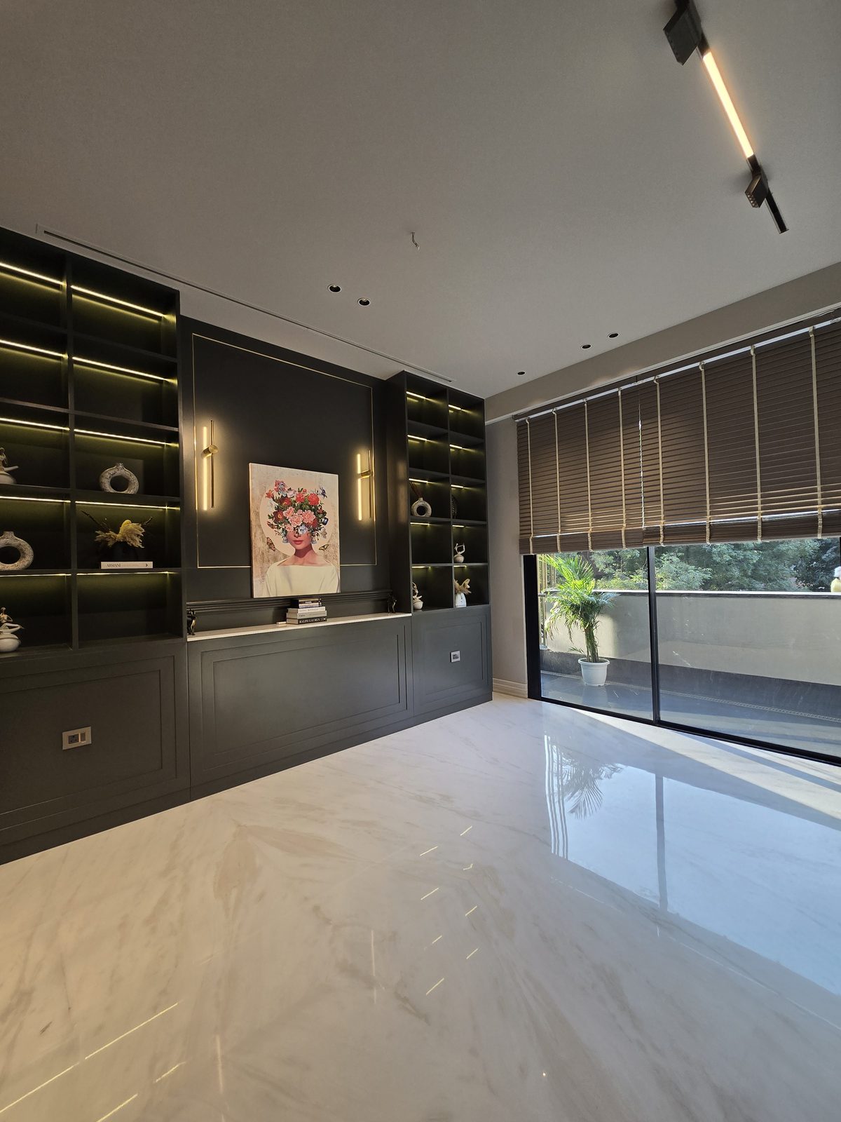 Study lounge in an Ekum Homes South Delhi builder floor with backlit dark joinery, white marble flooring and a balcony beyond
