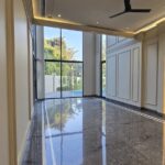 Double-height lounge with grey marble floor and garden-facing glass at an Indus Homes home