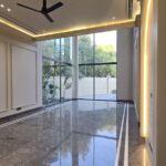 Family lounge with grey marble flooring and corner glazing in a builder floor in Greater Kailash 2, South Delhi