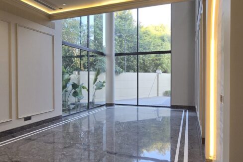 Family lounge with grey marble flooring and corner glazing in a builder floor in Greater Kailash 2, South Delhi