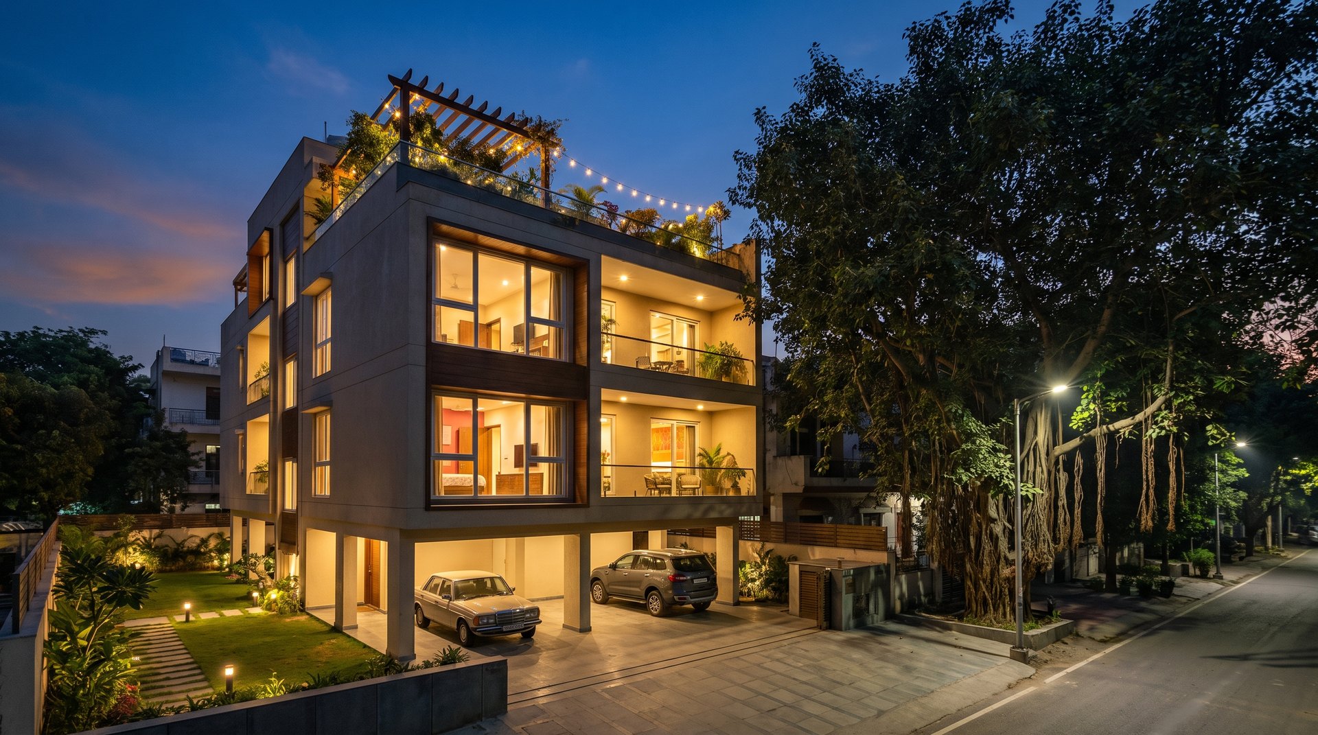 Best floor in a builder floor &mdash; a stilt-plus-four South Delhi building at blue hour with a ground-floor lawn and a lit terrace garden on the roof