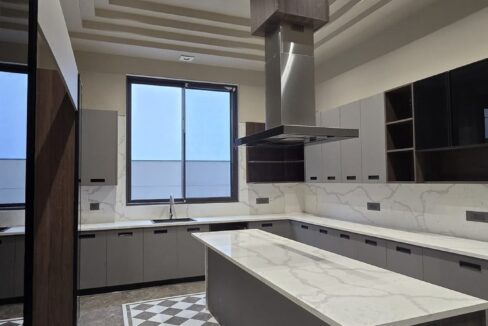 Modular kitchen with a marble island and checkerboard floor in a home by the developer of this 3 BHK in Panchsheel Enclave