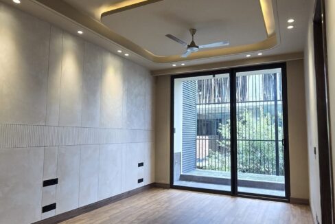 Bedroom with wooden flooring opening to a balcony in a home by the developer of this 4 BHK in GK-1