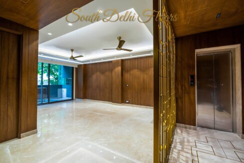 Living room with walnut wall panelling and a private lift lobby in a home by the developer of this 4 BHK in Safdarjung Enclave