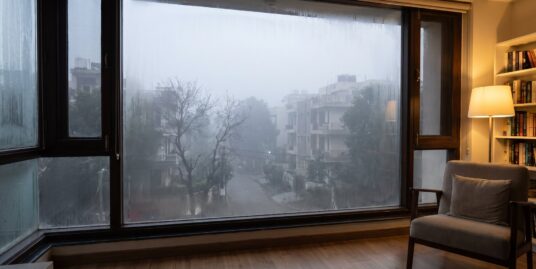 View from inside a South Delhi home through a sealed window at a hazy winter morning outside