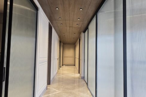 Corridor with fluted glass doors and a wood ceiling in a home by the developer of this builder floor in Panchsheel Park