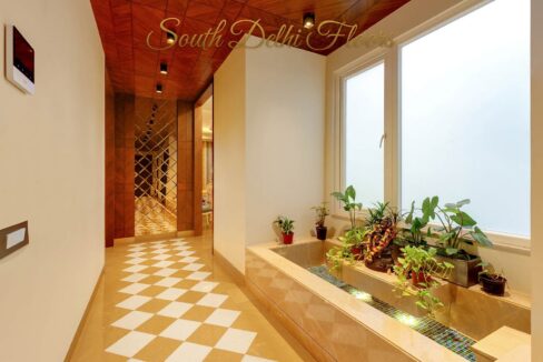 Entrance lobby with a planter bed and checkerboard marble floor in a home by the developer of this builder floor in South Extension 2