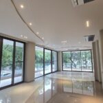 Living room with corner floor-to-ceiling glazing and green views in a home by the developer of the corner duplex in Panchsheel Park