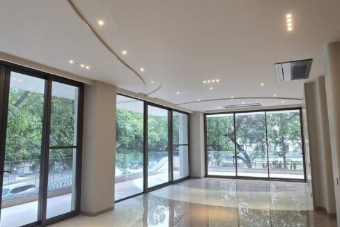 Living room with corner floor-to-ceiling glazing and green views in a home by the developer of the corner duplex in Panchsheel Park