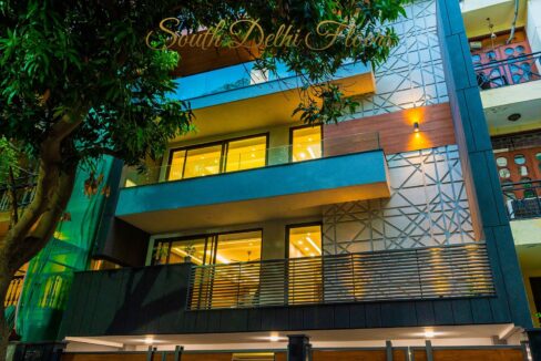 Night view of a corner building with glazed balconies by the developer of this corner property in Defence Colony