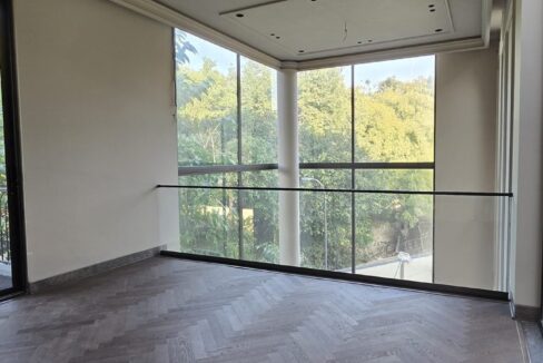 Double-height room with corner glazing and herringbone wood floor by the developer of this corner property in GK-3