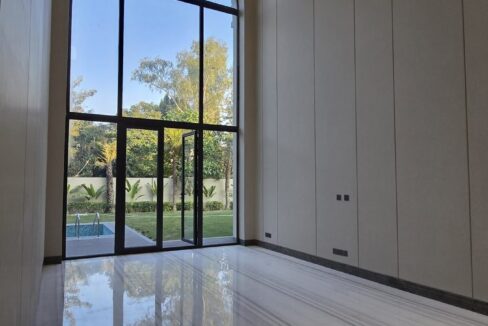 Double-height arched window looking onto a pool in a home by the developer of this duplex in Anand Niketan