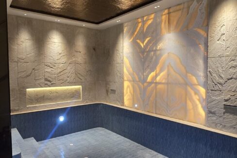 Indoor pool with a backlit onyx wall and curved steps in a home by the developer of the duplex with pool in Pamposh Enclave, GK-1
