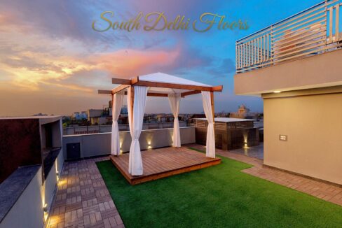 Rooftop terrace with a pergola lounge and lawn by the developer of this east-facing home in Panchsheel Enclave