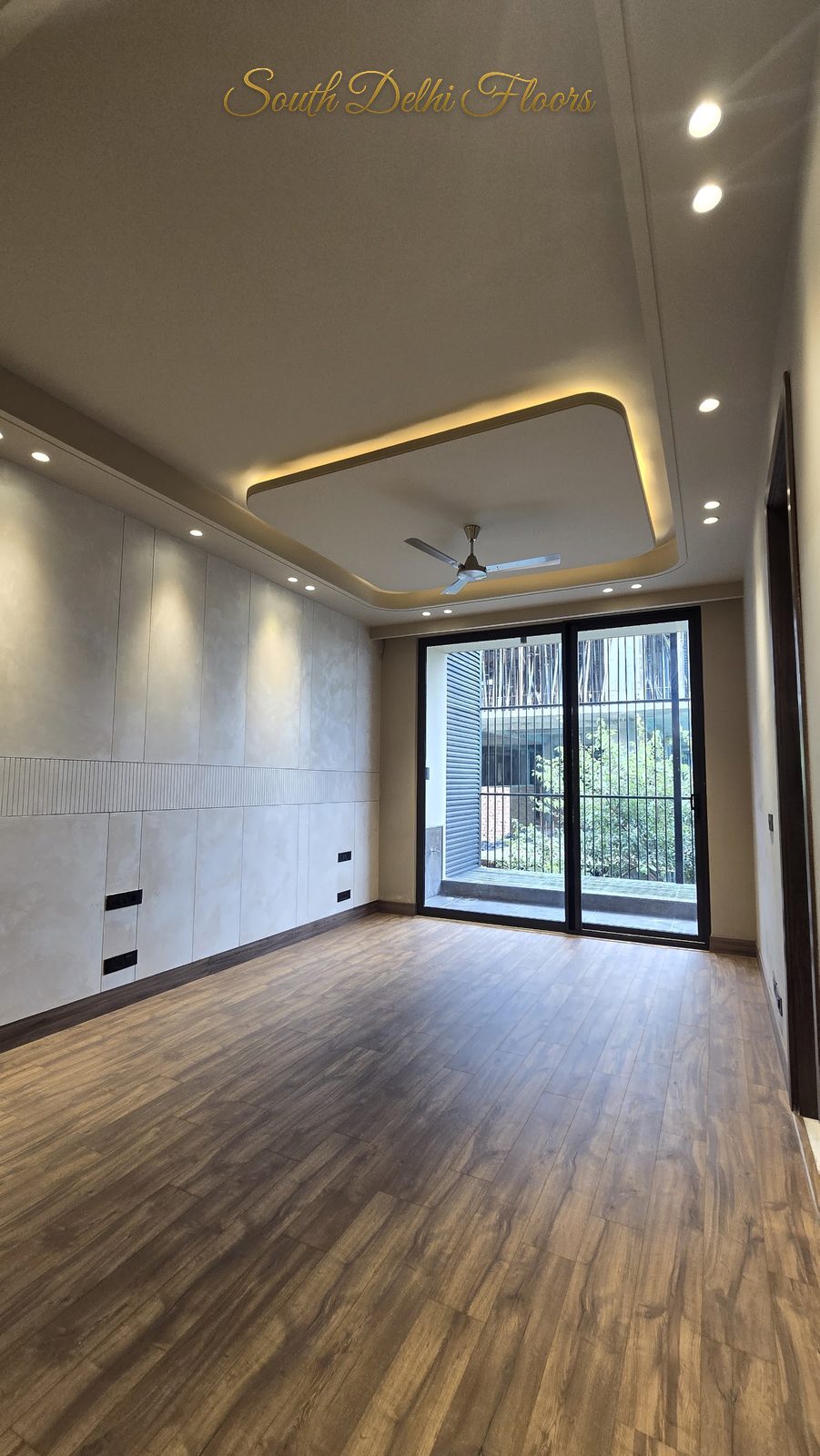 Fourth bedroom with engineered wooden flooring, cove-lit ceiling and balcony glazing at an Indus Homes builder floor in GK-1, South Delhi