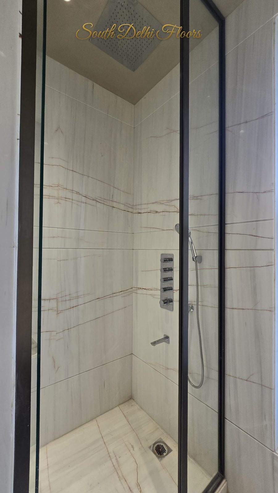 Glass shower cubicle in light veined marble with multi-jet shower panel at an Indus Homes builder floor in Greater Kailash-1, South Delhi