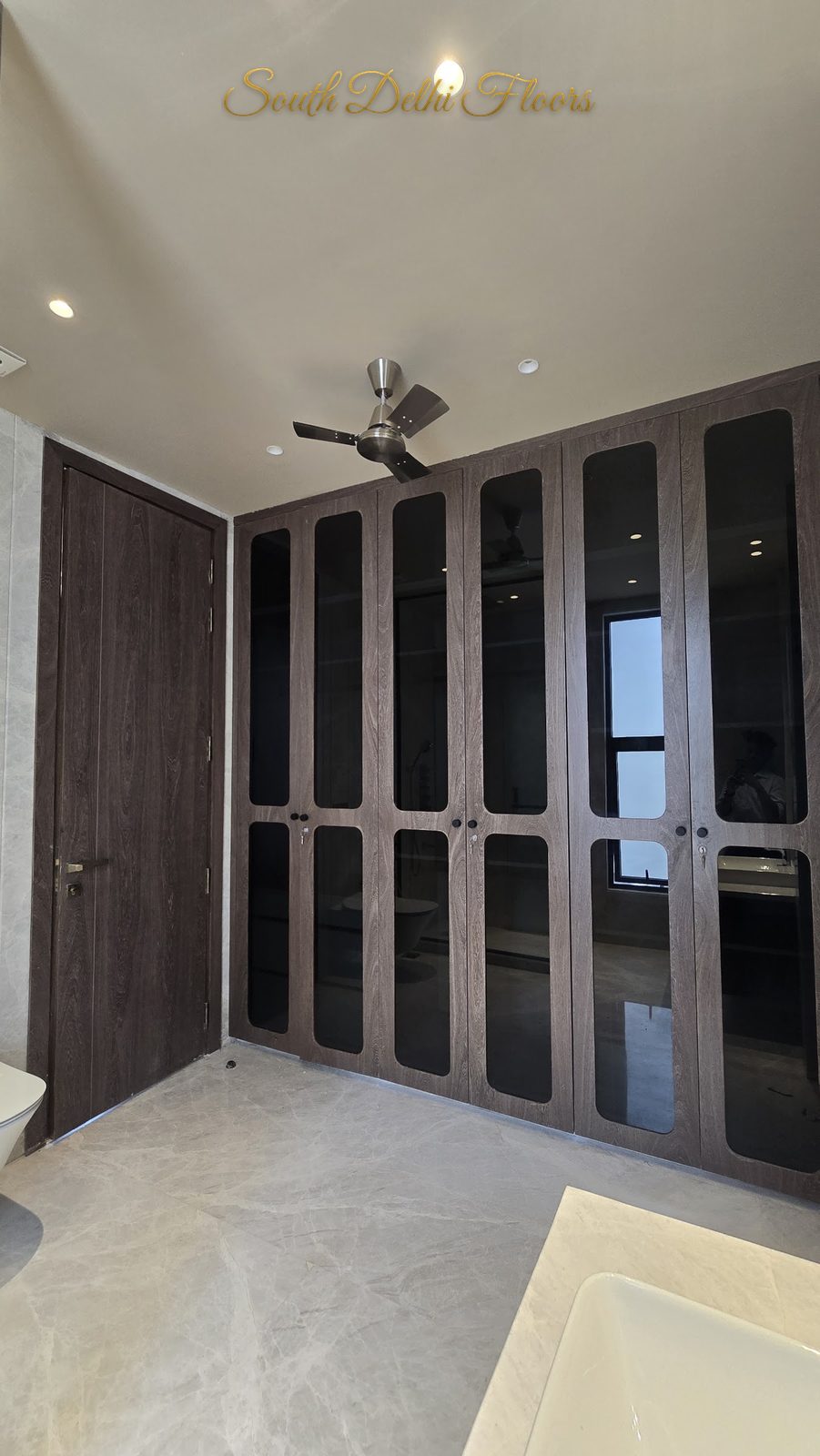 Walk-in closet with six glass-fronted wardrobe doors in dark wood frames at an Indus Homes builder floor in Greater Kailash-1, South Delhi