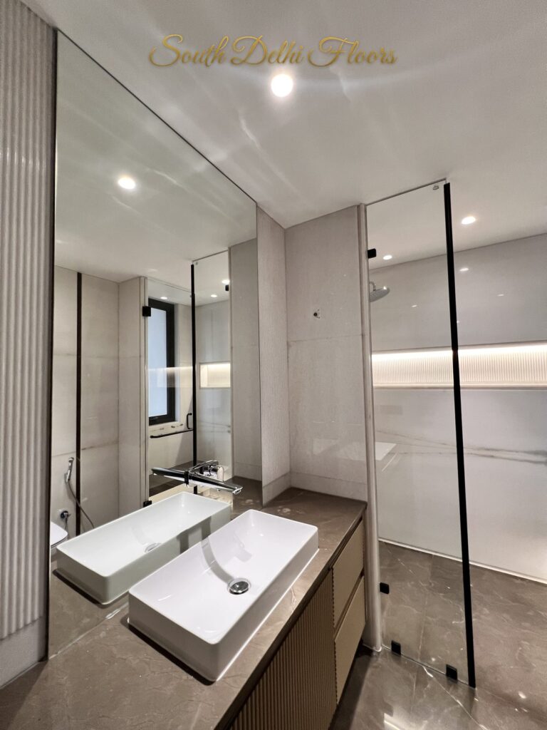 Bathroom with a fluted wood vanity, stone countertop and full-width mirror at a Katarias luxury home in South Delhi by builder Sandeep Kataria