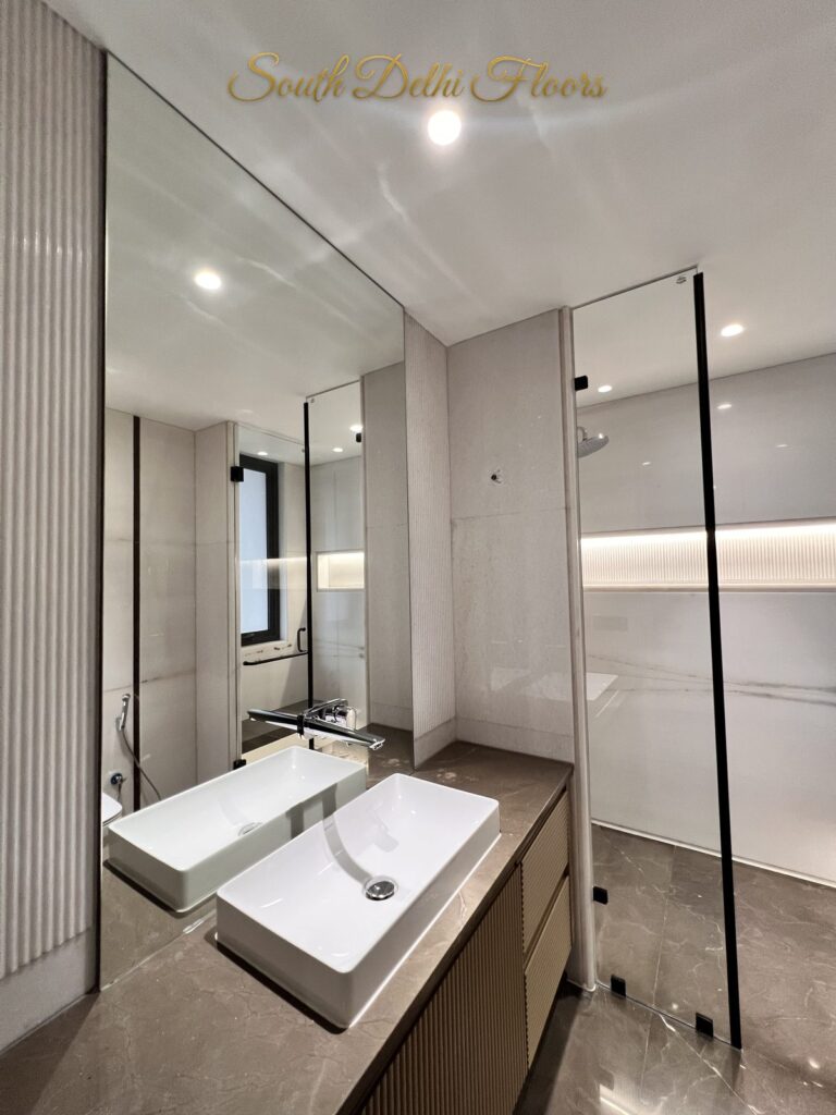Bathroom with a rectangular vessel basin on a stone counter beside a black-framed glass shower at a Katarias luxury residence in South Delhi by developer Sandeep Kataria