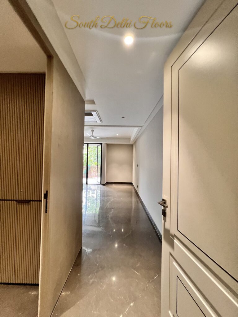 Bedroom entry passage with a fluted wardrobe, panelled door and brown marble flooring at a Katarias luxury home in South Delhi by builder Sandeep Kataria