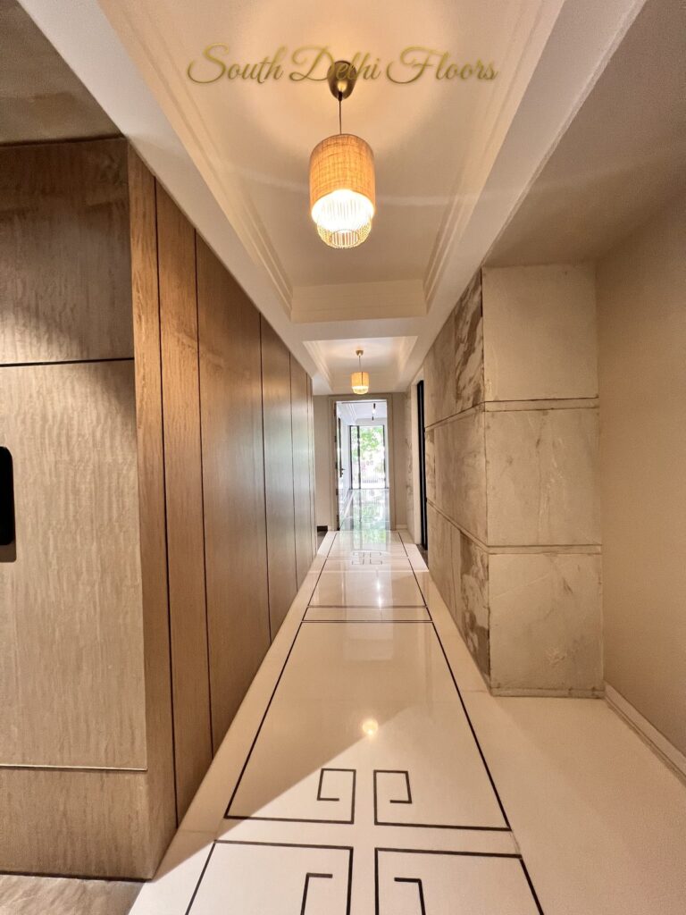 Marble-floored corridor with a glowing rattan pendant and wood veneer walls at a Katarias luxury home in South Delhi by builder Sandeep Kataria