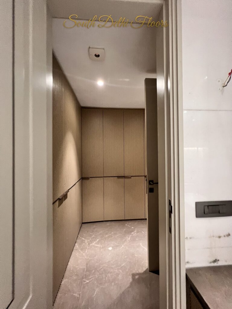 Dressing room with floor-to-ceiling fluted wardrobes and marble flooring at a Katarias luxury builder floor in South Delhi by Sandeep Kataria