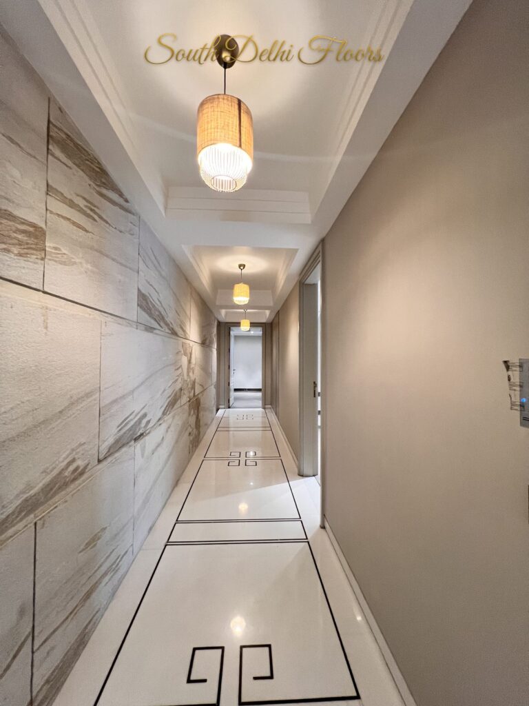 Entrance corridor with a rattan pendant light, veined stone wall cladding and a black Greek key inlay in white marble at a Katarias luxury home in South Delhi by builder Sandeep Kataria