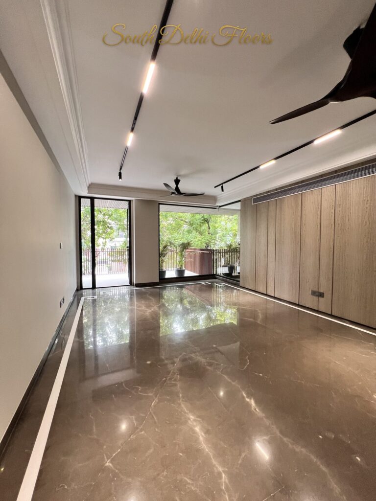 Living room with black track lights, black ceiling fans and glossy brown marble floors at a Katarias luxury home in South Delhi by builder Sandeep Kataria