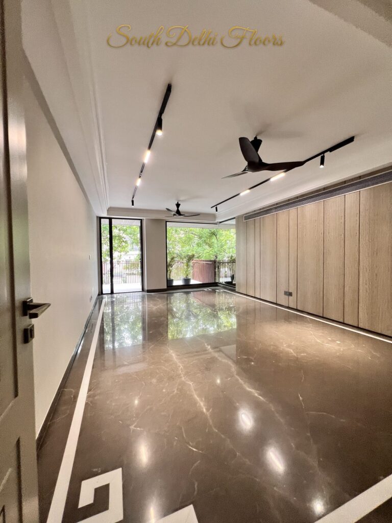 Living room with brown veined marble flooring framed by a white Greek key border at a Katarias luxury builder floor in South Delhi by Sandeep Kataria