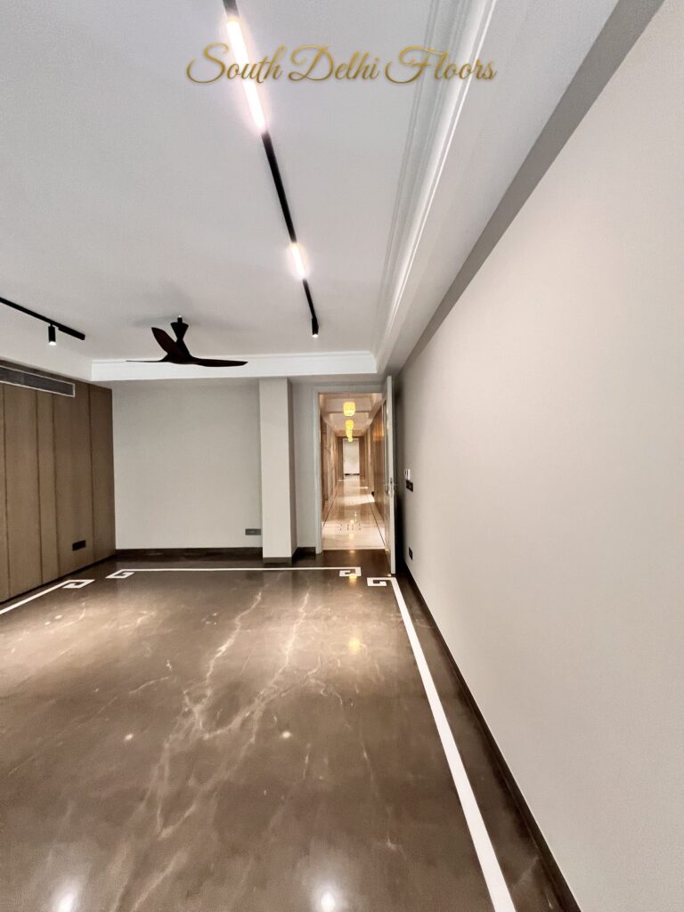 Living room looking towards the entrance corridor, with brown marble flooring and a Greek key border at a Katarias luxury builder floor in South Delhi by Sandeep Kataria