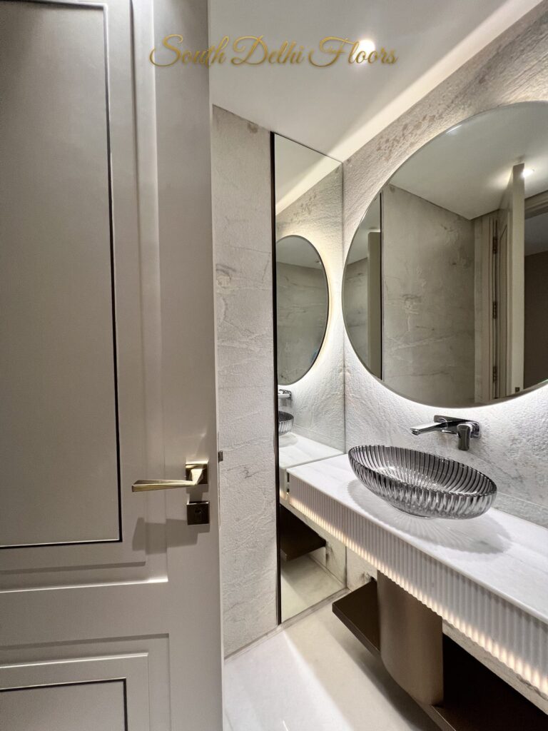 Powder room vanity glimpsed through a panelled door with a brass handle at a Katarias luxury residence in South Delhi by developer Sandeep Kataria