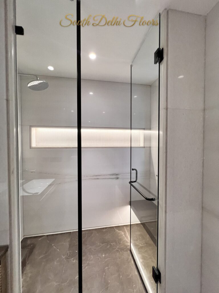 Walk-in shower with frameless glass doors, a rain shower head and an illuminated niche at a Katarias luxury residence in South Delhi by developer Sandeep Kataria