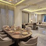 Furnished dining and living room of the penthouse in Shanti Niketan with a chandelier and marble floors