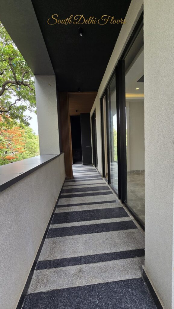 Balcony with tree canopy view, wooden slat wall and granite floor at an RPB Homes JCR Homes luxury property in South Delhi by Mahavir Bihani and Rajat Bihani