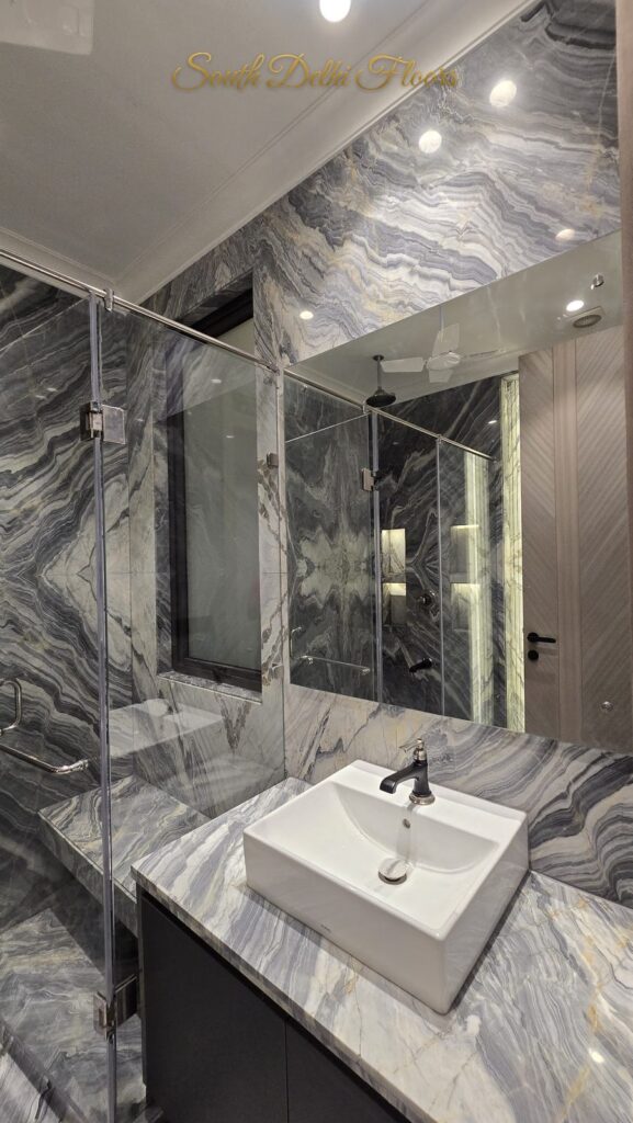 Bathroom with book-matched grey marble, glass shower and basin at an RPB Homes JCR Homes luxury builder floor in South Delhi by Mahavir Bihani and Rajat Bihani