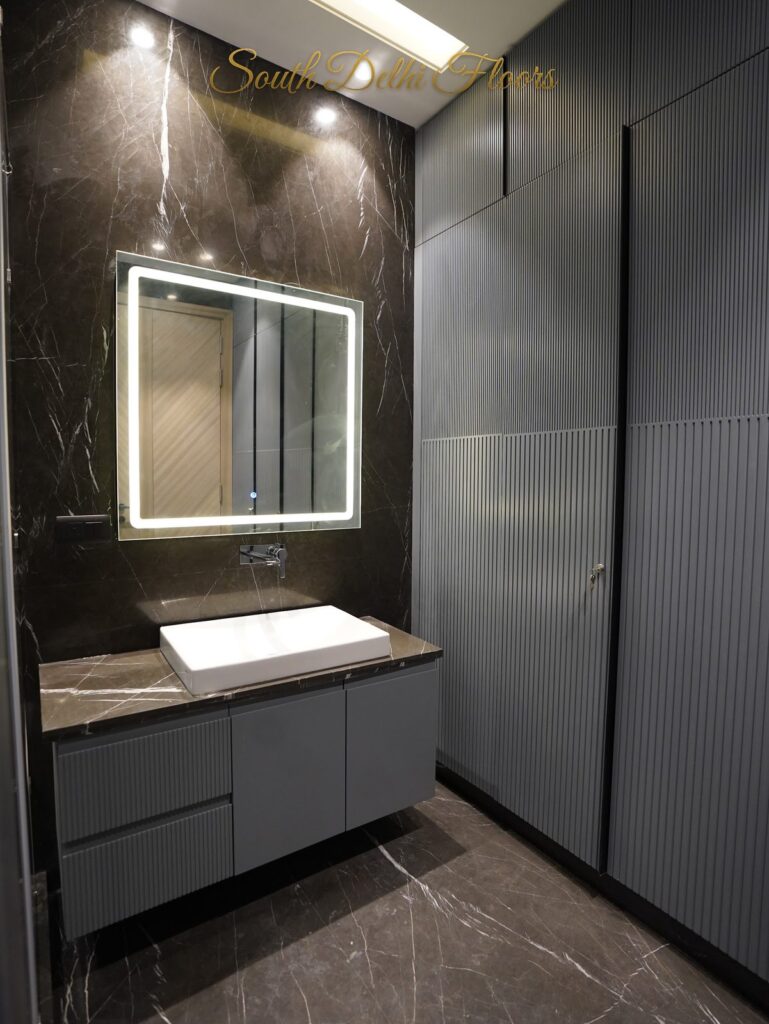 Bathroom with dark veined marble, an LED mirror and grey fluted vanity at an RPB Homes JCR Homes luxury property in South Delhi by Mahavir Bihani and Rajat Bihani