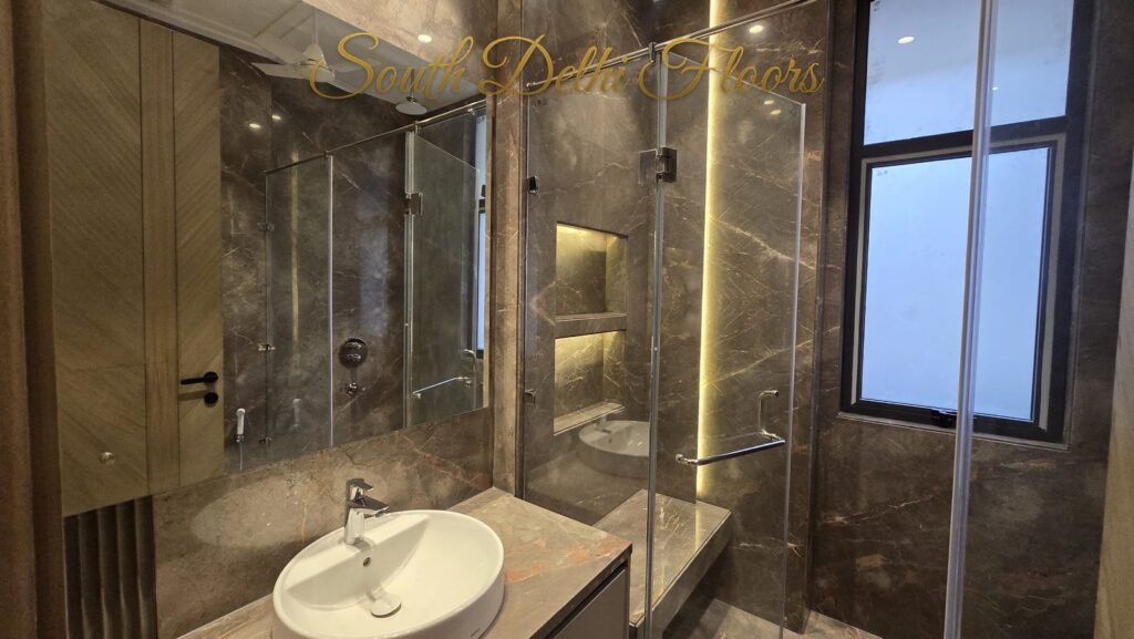 Bathroom with veined marble, a lit niche, window and round basin at an RPB Homes JCR Homes luxury home in South Delhi by builders Mahavir Bihani and Rajat Bihani