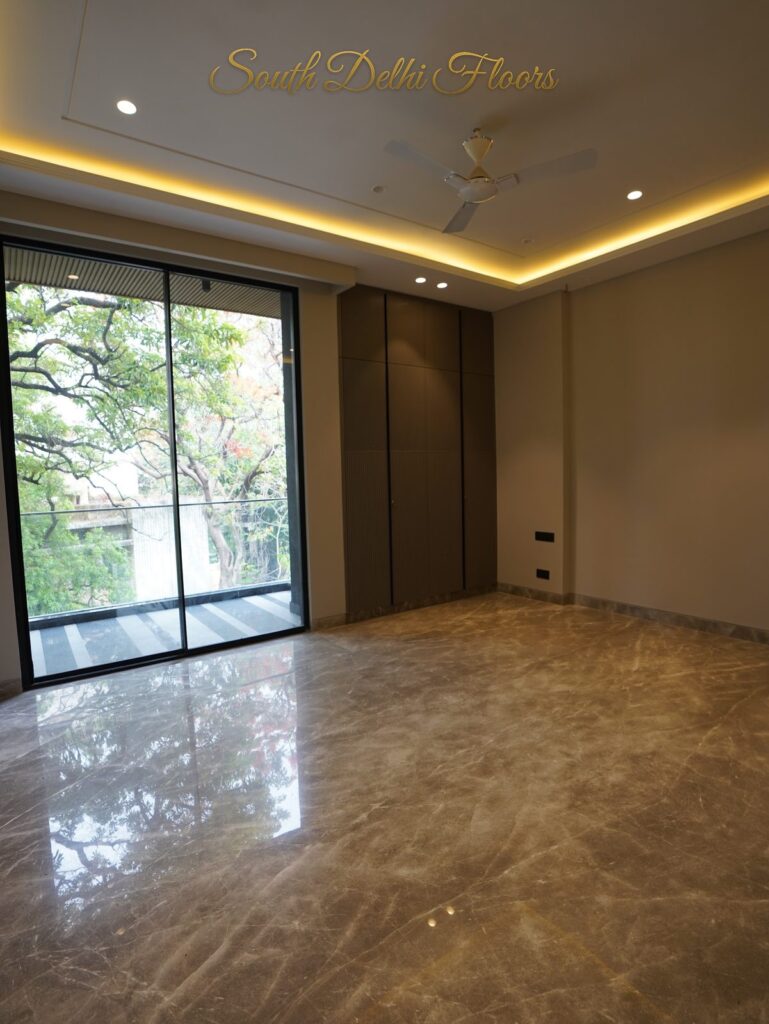 Bedroom with a cove-lit ceiling and black-framed glass opening onto a green tree view at an RPB Homes JCR Homes luxury property in South Delhi by Mahavir Bihani and Rajat Bihani