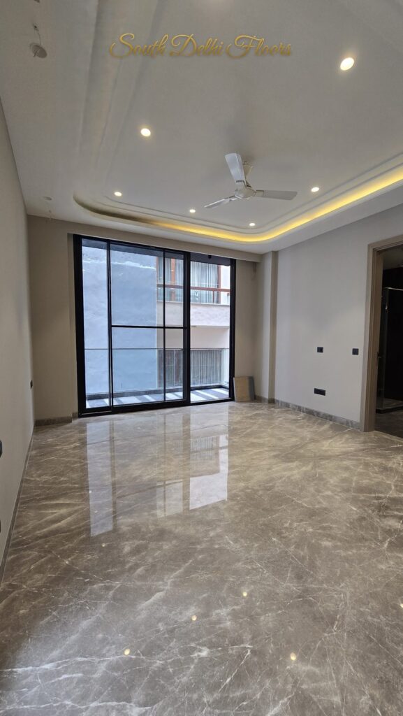 Bedroom with curved cove lighting, a balcony glass door and polished marble floor at an RPB Homes JCR Homes luxury residence in South Delhi by developers Mahavir Bihani and Rajat Bihani