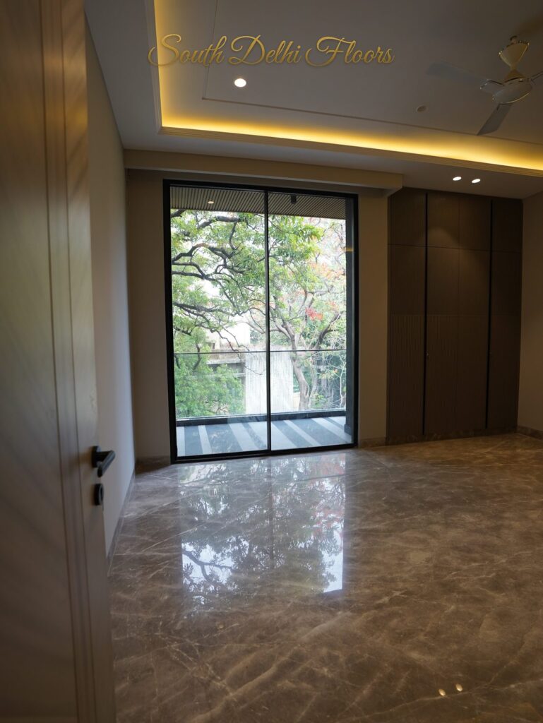 Bedroom with a fluted wall panel, polished marble floor and glass door to the balcony at an RPB Homes JCR Homes luxury builder floor in South Delhi by Mahavir Bihani and Rajat Bihani