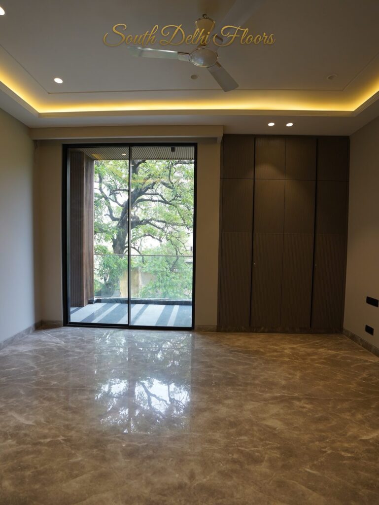 Bedroom with a fluted wardrobe and tree-view balcony door at an RPB Homes JCR Homes luxury builder floor in South Delhi by Mahavir Bihani and Rajat Bihani