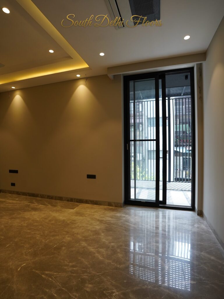 Bedroom with a glass balcony door and recessed cove lighting at an RPB Homes JCR Homes luxury builder floor in South Delhi by Mahavir Bihani and Rajat Bihani