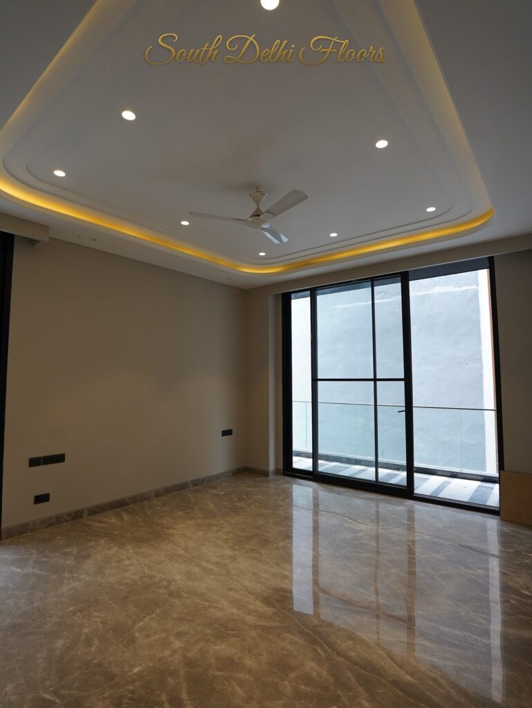 Bedroom with a sculpted cove-lit ceiling and balcony glass door at an RPB Homes JCR Homes luxury home in South Delhi by builders Mahavir Bihani and Rajat Bihani